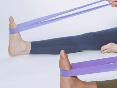 A pair of dumbbells and a resistance band neatly placed on a yoga mat.